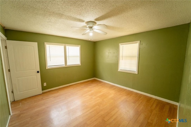 spare room featuring baseboards, a ceiling fan, a textured ceiling, and light wood-type flooring