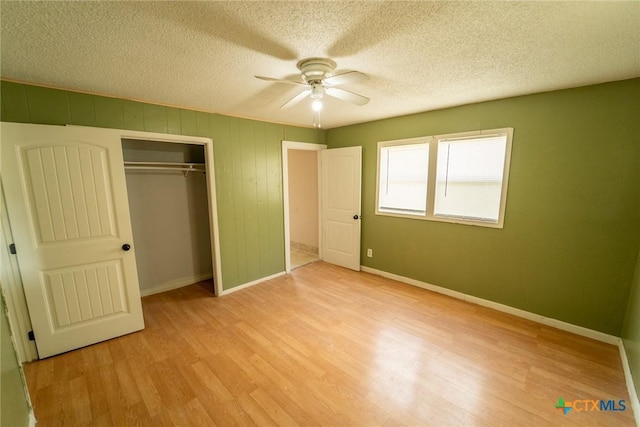 unfurnished bedroom featuring a textured ceiling, wood finished floors, a closet, and baseboards