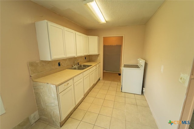 kitchen featuring light countertops, white cabinetry, a sink, and washer / clothes dryer