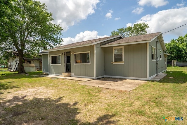 back of property featuring fence, a lawn, and a patio area
