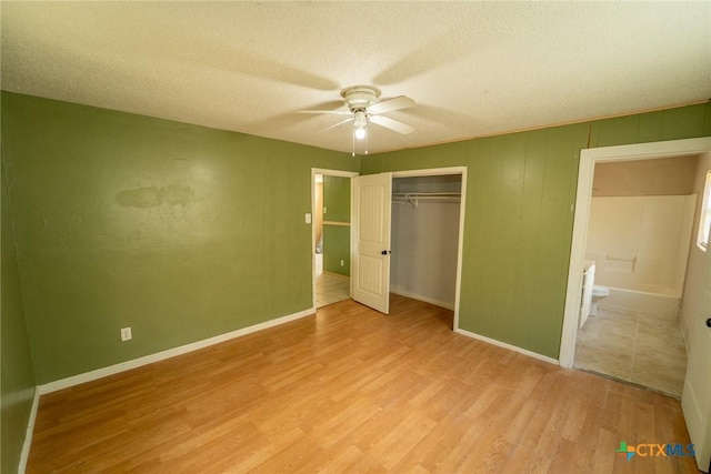 unfurnished bedroom featuring a textured ceiling, wood finished floors, a closet, and baseboards