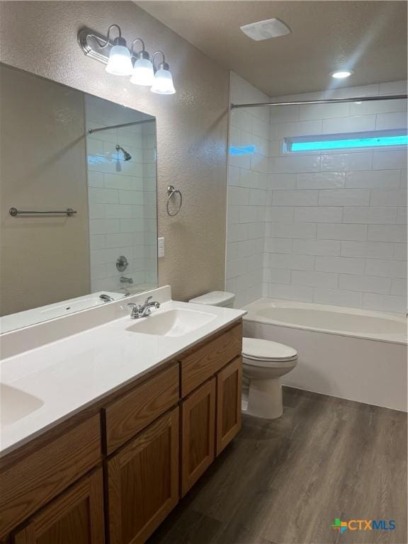 full bathroom featuring tiled shower / bath, toilet, vanity, and hardwood / wood-style flooring