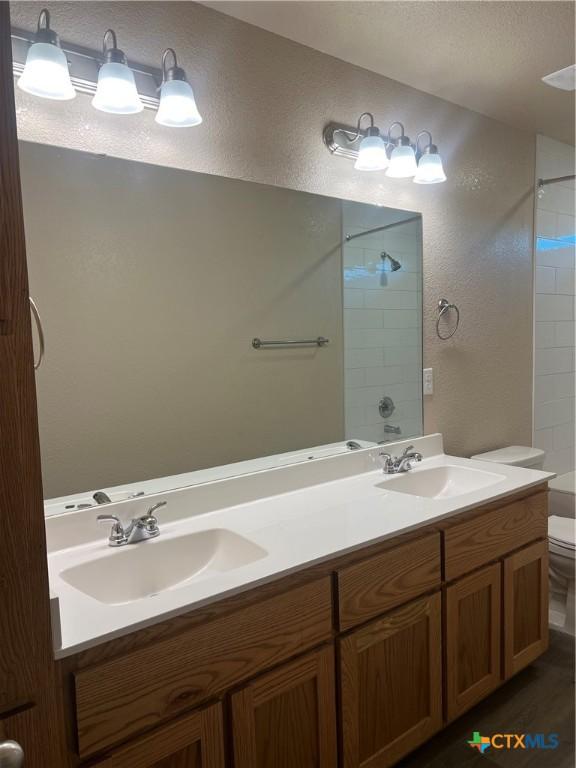 bathroom featuring tiled shower, vanity, and toilet