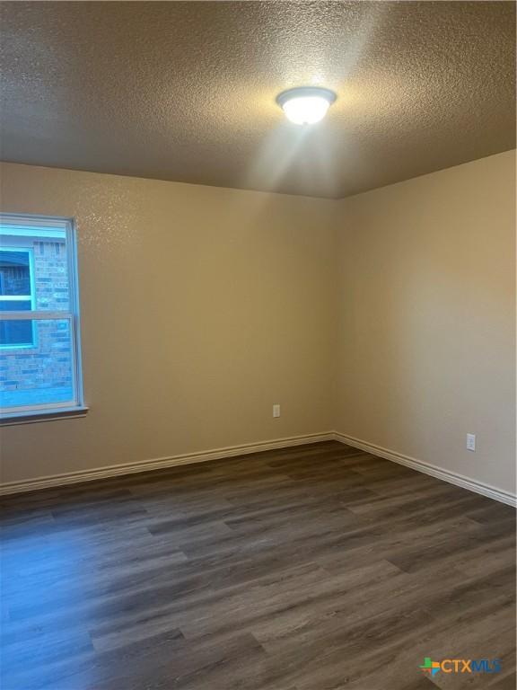 empty room featuring a textured ceiling and dark hardwood / wood-style floors