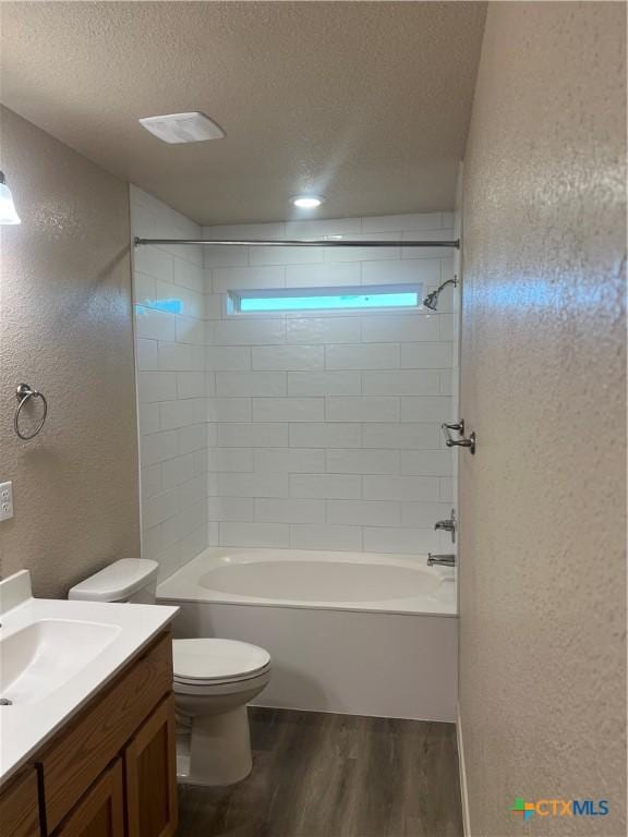 full bathroom featuring vanity, a textured ceiling, hardwood / wood-style flooring, toilet, and tiled shower / bath