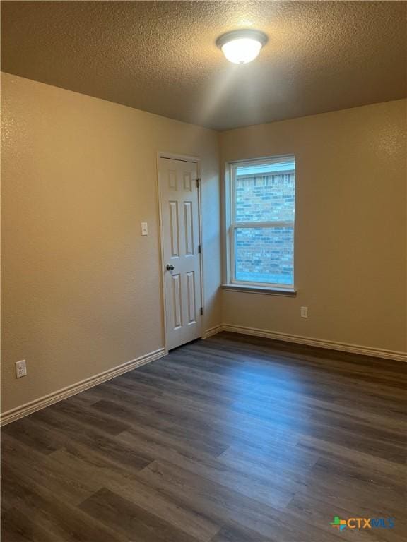 spare room with dark hardwood / wood-style flooring and a textured ceiling