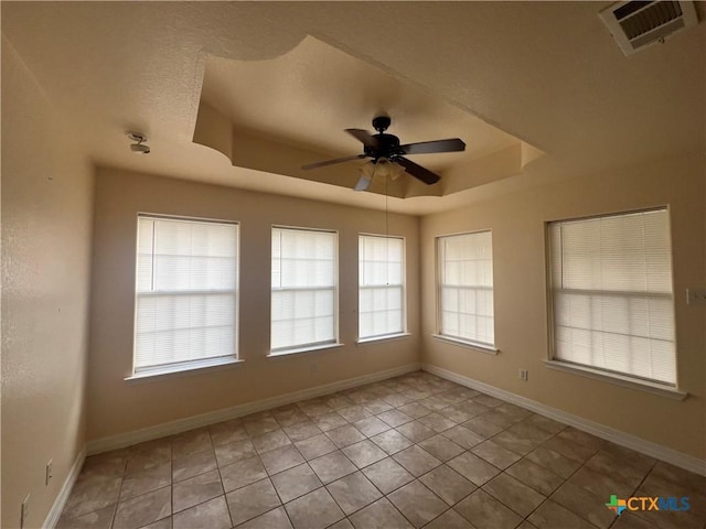 tiled spare room with ceiling fan and a raised ceiling