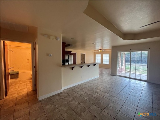 unfurnished living room with tile patterned flooring, a textured ceiling, and ceiling fan