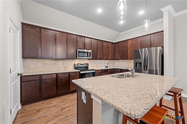 kitchen with appliances with stainless steel finishes, sink, pendant lighting, a breakfast bar area, and an island with sink