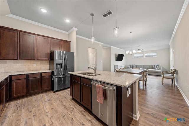 kitchen featuring pendant lighting, sink, light hardwood / wood-style floors, light stone counters, and stainless steel appliances