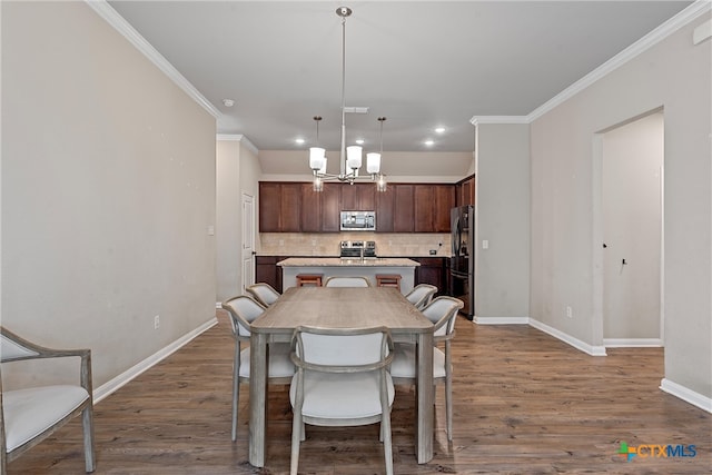 dining space with crown molding, dark hardwood / wood-style flooring, and an inviting chandelier