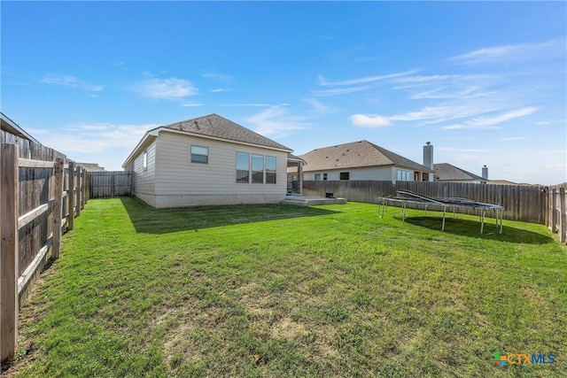 rear view of house featuring a yard and a trampoline