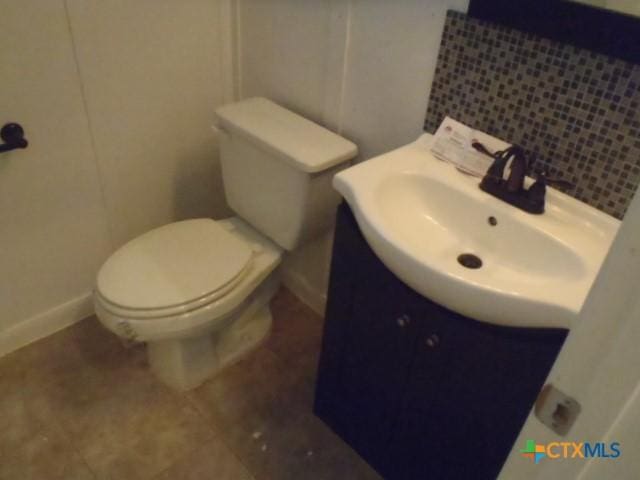 bathroom featuring vanity, toilet, and backsplash