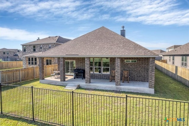 back of house featuring roof with shingles, a chimney, brick siding, and a patio area