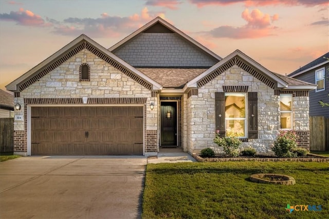 324 Linden St, Bastrop, TX 78602 - french country inspired facade featuring an attached garage, concrete driveway, a front lawn, stone siding, and roof with shingles