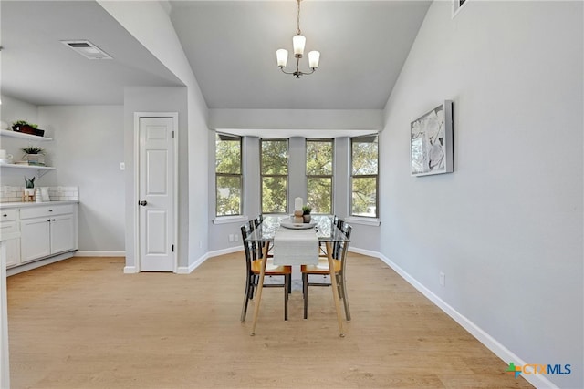 dining area featuring light hardwood / wood-style floors, vaulted ceiling, and a notable chandelier