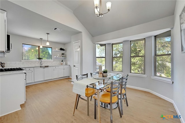 dining space featuring light hardwood / wood-style floors, lofted ceiling, sink, and a wealth of natural light