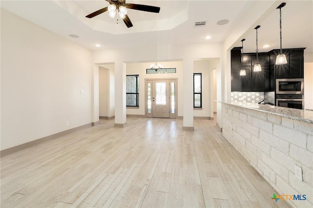 2892 Beulah Blvd, Belton, TX 76513 - unfurnished living room featuring a tray ceiling, light wood-type flooring, ceiling fan, a chandelier, and recessed lighting