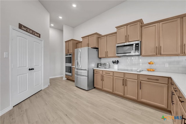 kitchen with appliances with stainless steel finishes, light hardwood / wood-style floors, and decorative backsplash