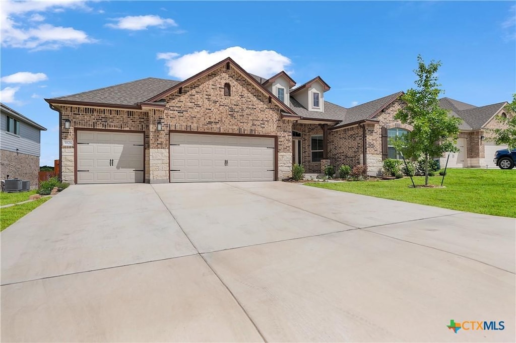 view of front of home featuring a garage, a front yard, and central air condition unit