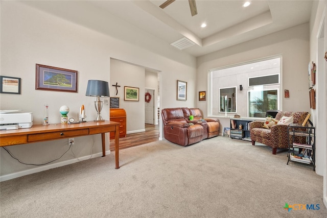 sitting room featuring carpet flooring, ceiling fan, and a raised ceiling