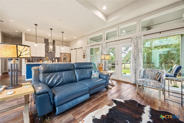 living room with dark wood-type flooring, a barn door, and french doors