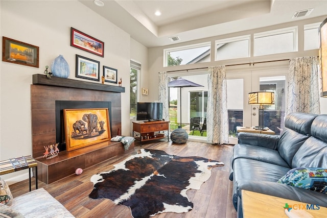 living room featuring hardwood / wood-style flooring, a towering ceiling, a raised ceiling, and french doors