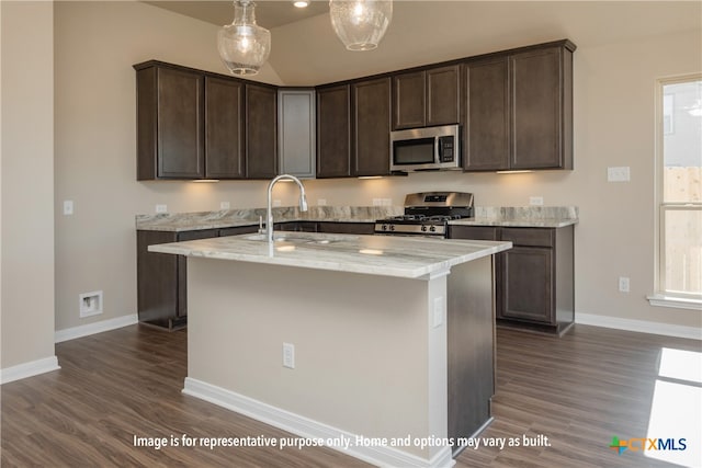 kitchen with dark brown cabinets, appliances with stainless steel finishes, dark hardwood / wood-style floors, and light stone countertops