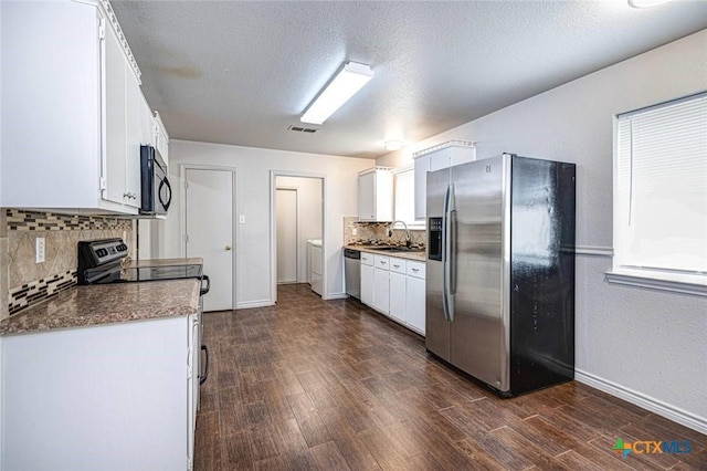 kitchen with white cabinets, appliances with stainless steel finishes, dark hardwood / wood-style flooring, and washer and clothes dryer