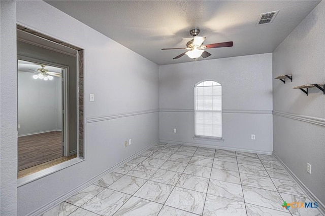 unfurnished room featuring ceiling fan and a textured ceiling