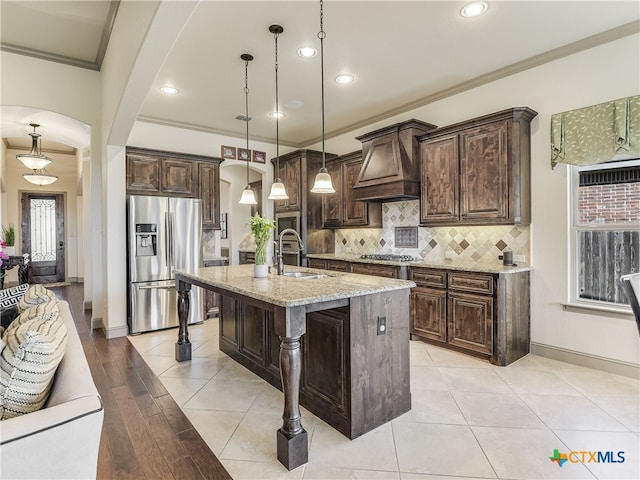535 Mission Hill Run, New Braunfels, TX 78132 - kitchen with appliances with stainless steel finishes, arched walkways, custom exhaust hood, dark brown cabinetry, and recessed lighting
