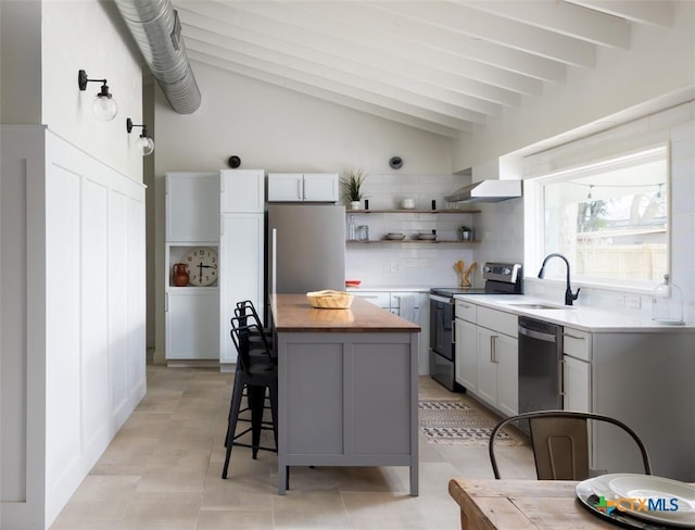 119 W Crockett St, Luling, TX 78648 - kitchen with stainless steel appliances, wood counters, vaulted ceiling, open shelves, and wall chimney range hood