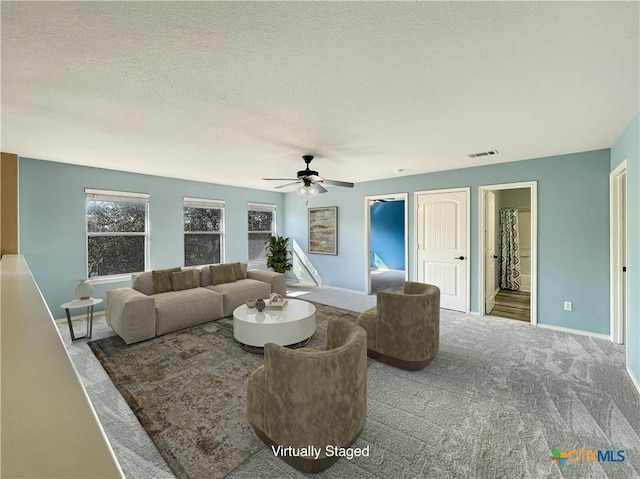 carpeted living room with ceiling fan and a textured ceiling