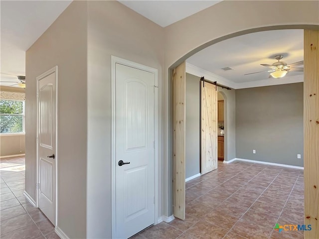 hall featuring crown molding, tile patterned floors, and a barn door