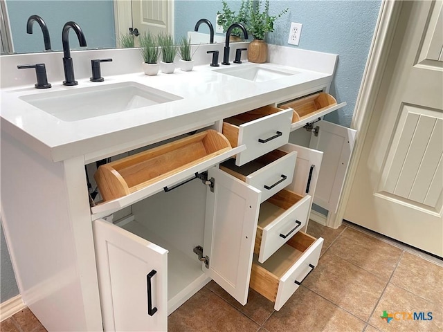 bathroom featuring double vanity, tile patterned floors, a sink, and a textured wall