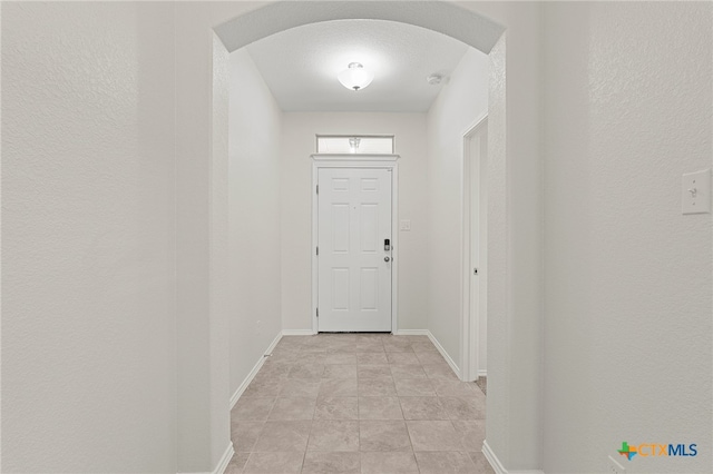 doorway to outside with baseboards and arched walkways