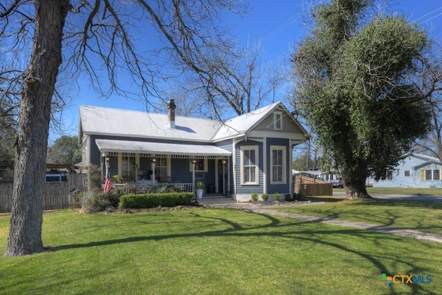 bungalow with covered porch, a chimney, a front yard, and fence