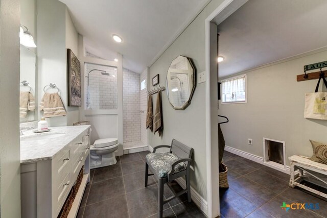 full bathroom with vanity, tiled shower, lofted ceiling, tile patterned floors, and toilet