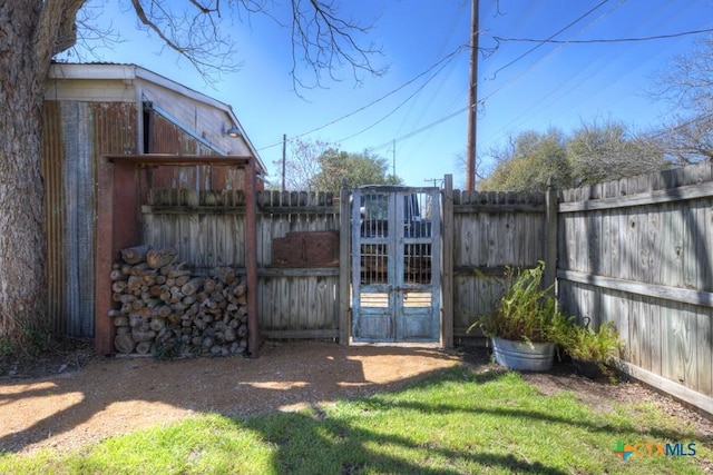 view of gate with a yard and a fenced backyard