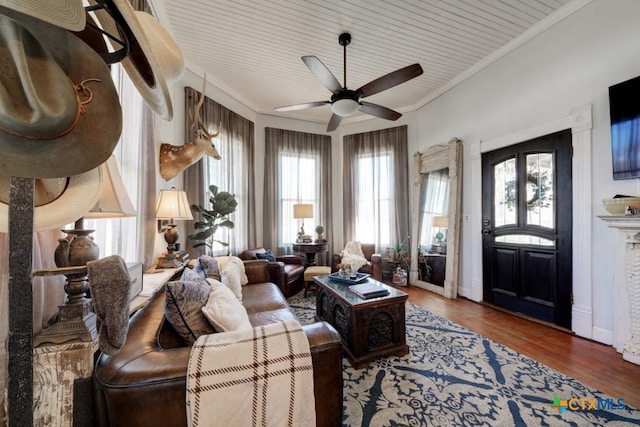 living area with ornamental molding, baseboards, a ceiling fan, and wood finished floors