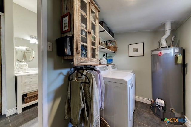 washroom featuring dark tile patterned floors, washing machine and dryer, water heater, baseboards, and laundry area