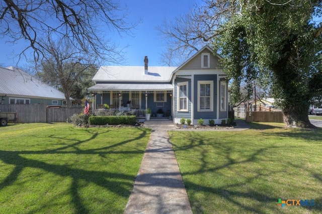 view of front of house with a front lawn, covered porch, a chimney, and fence