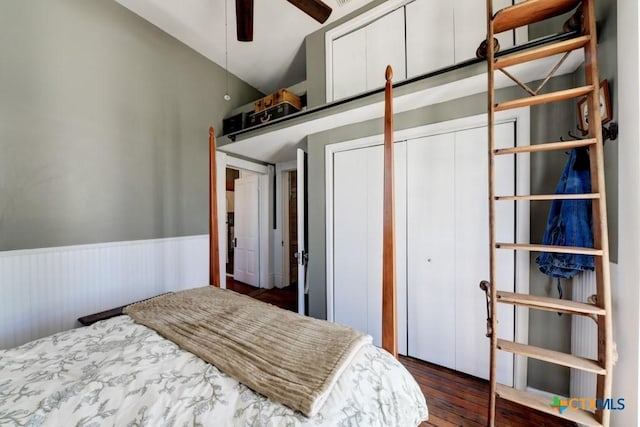 bedroom with a ceiling fan, wood finished floors, wainscoting, and vaulted ceiling