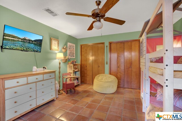 tiled bedroom with multiple closets and ceiling fan