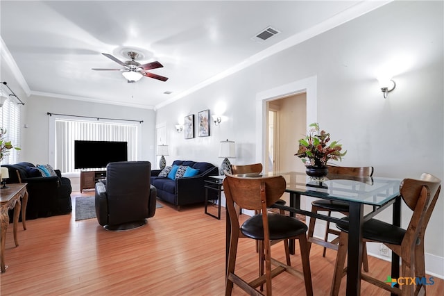 dining area featuring light wood-type flooring, ceiling fan, and crown molding