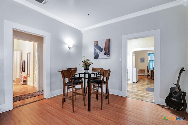 dining area with wood-type flooring and crown molding