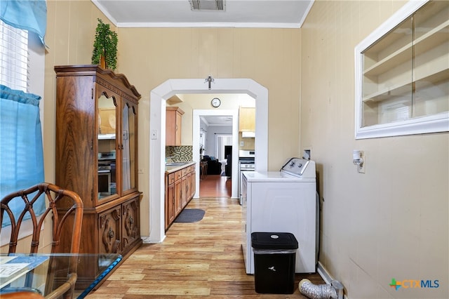 kitchen with decorative backsplash, light hardwood / wood-style floors, crown molding, and washer / dryer