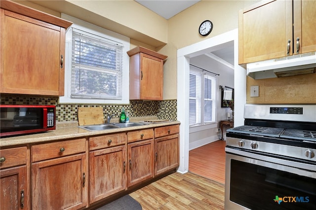 kitchen featuring light hardwood / wood-style flooring, sink, backsplash, and stainless steel gas range oven