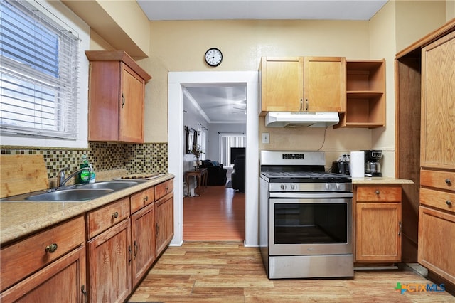 kitchen with sink, gas stove, ornamental molding, backsplash, and light hardwood / wood-style flooring