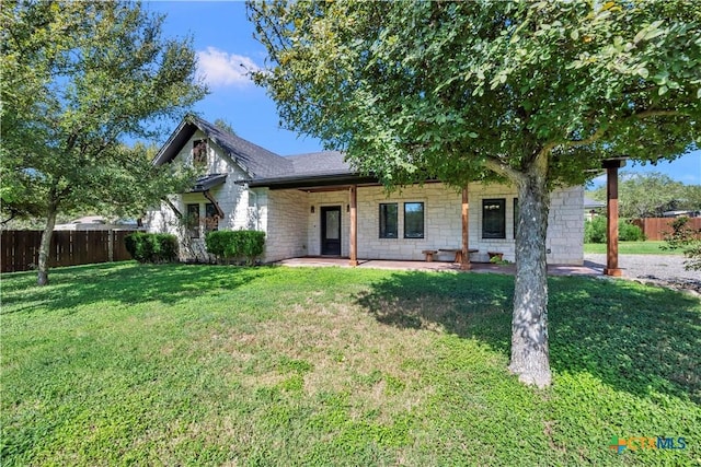 view of front of house with roof with shingles, a patio, fence, stone siding, and a front lawn